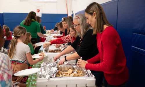 Adult volunteers serve children dinner