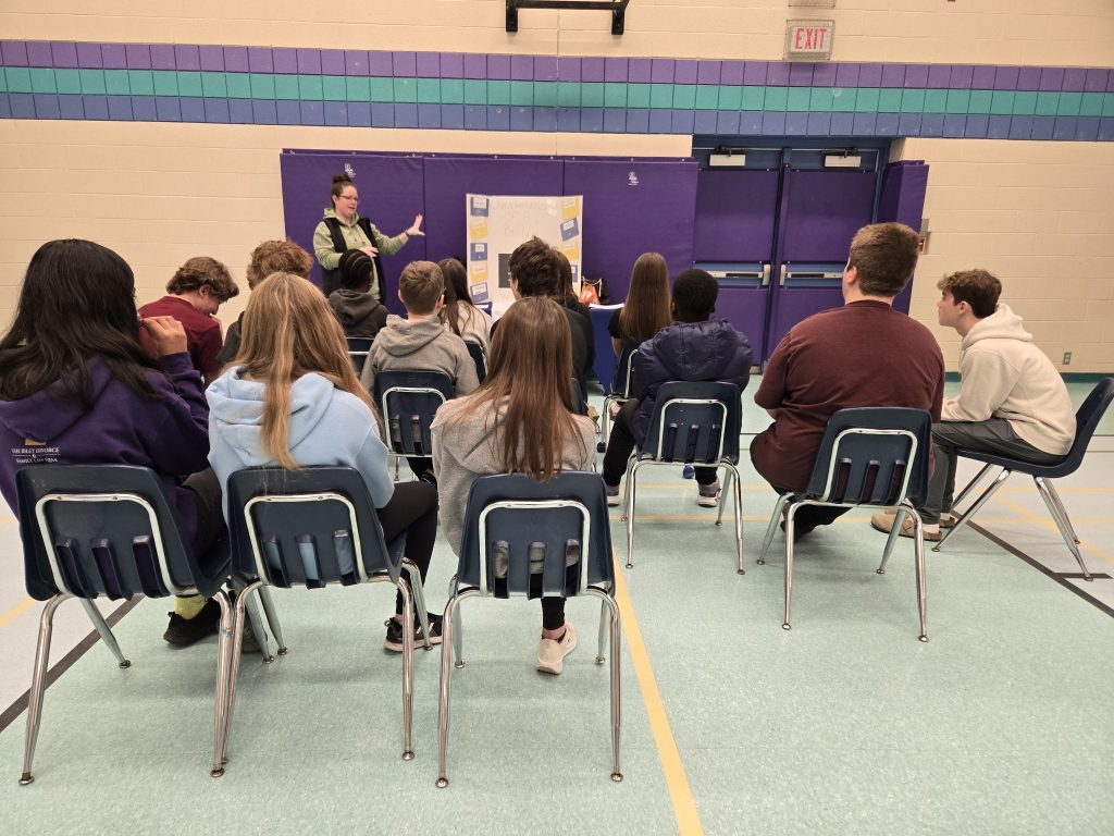 Group of students sitting in chairs while listening to a presenter.