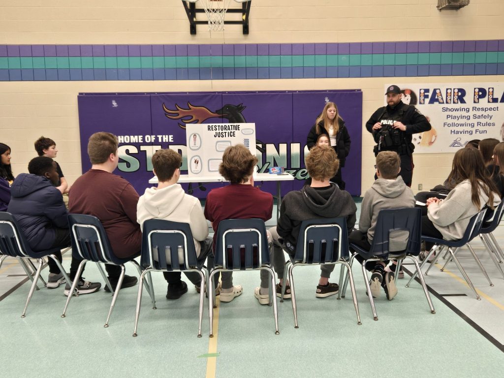 Group of students sitting in chairs while listening to a presenter.