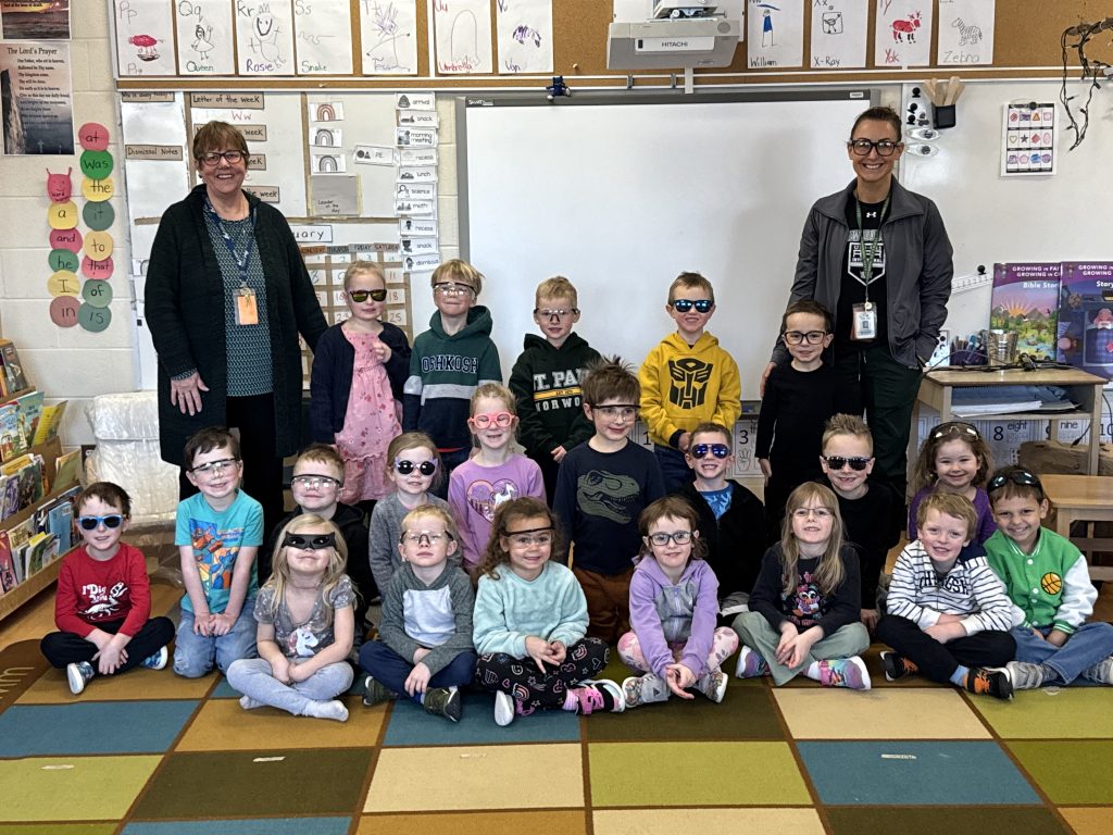 Class photo of students and educators wearing glasses.