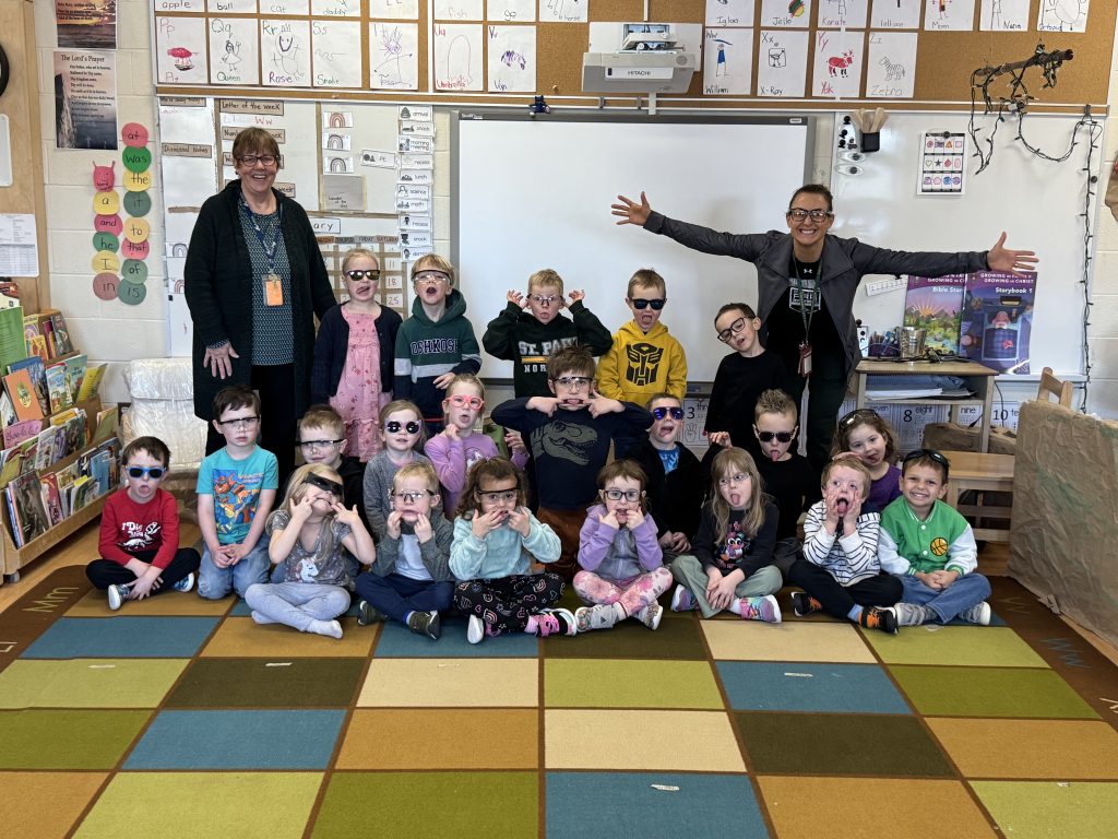 Class photo of students and educators wearing glasses.
