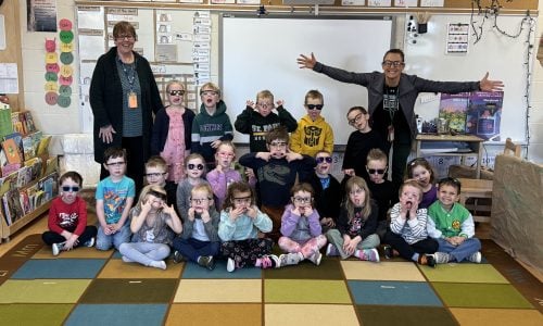 Class photo of students and educators wearing glasses.