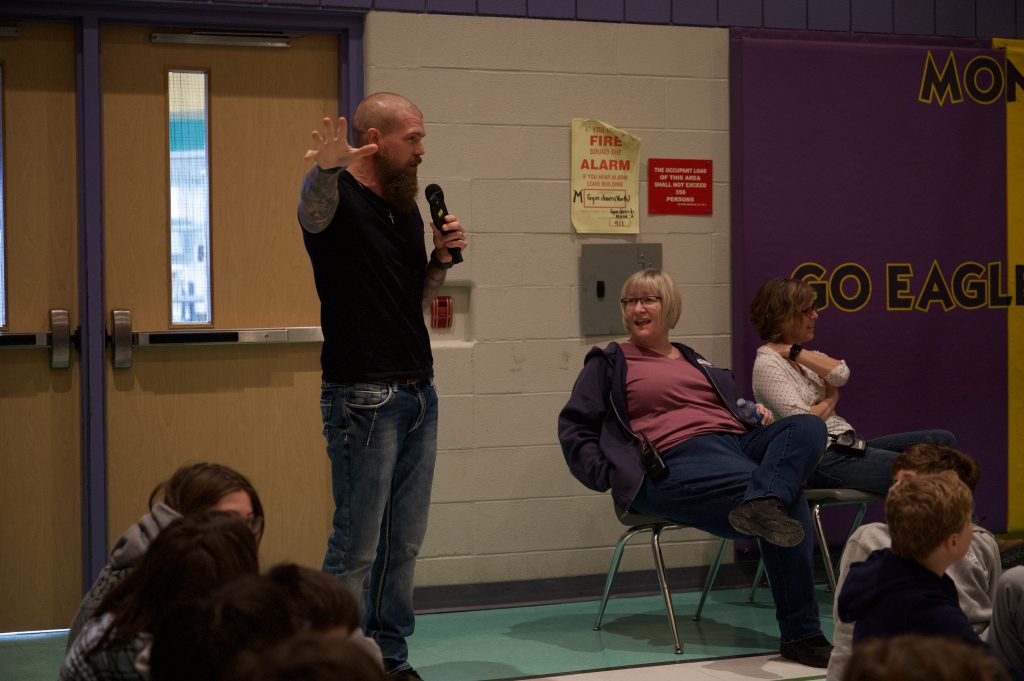 Man gives presentation to a room full of kids.
