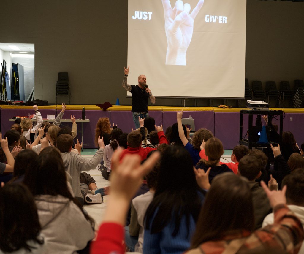 Man gives presentation to a room full of kids.