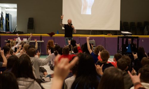 Man gives presentation to a room full of kids.