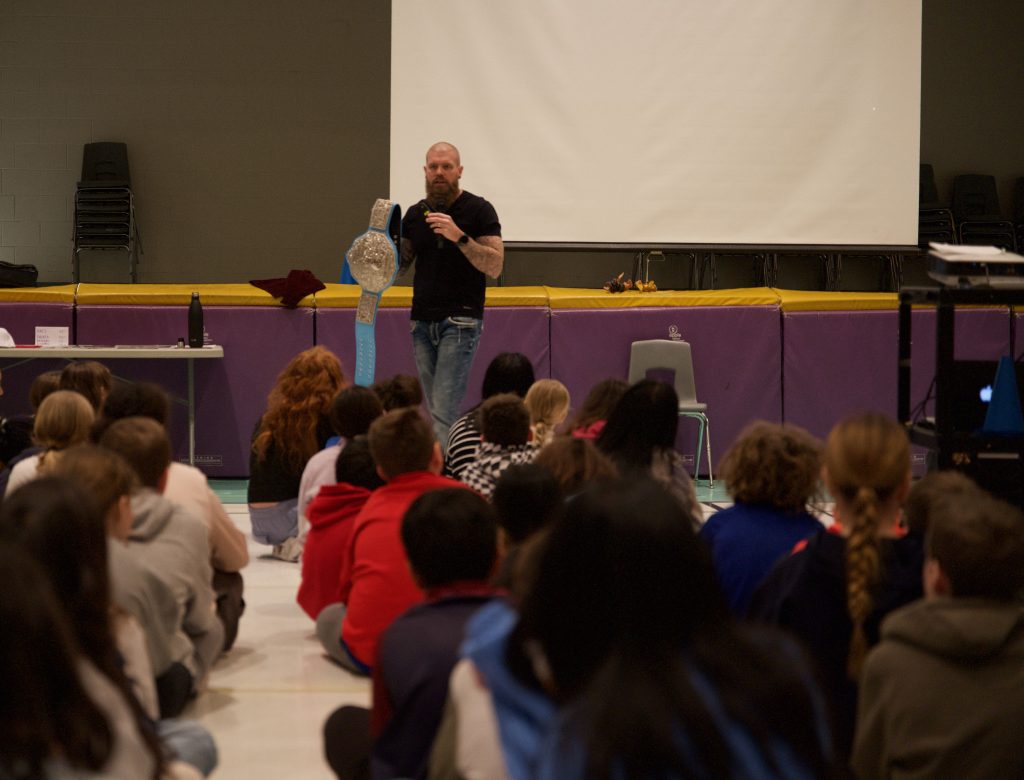 Man gives presentation to a room full of kids.