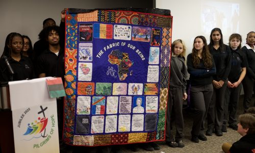 Group of students hold up a quilt created for Black History Month.
