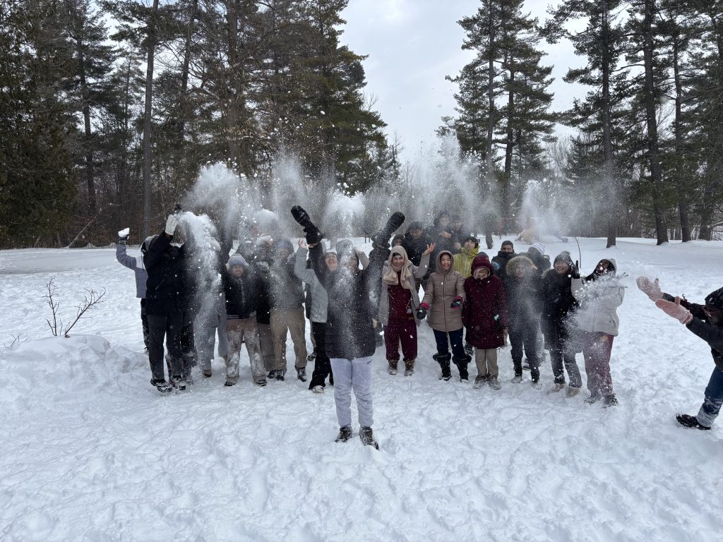 Group of students throwing snow into the air for a photo.