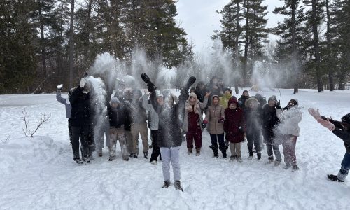 Group of students throwing snow into the air for a photo.