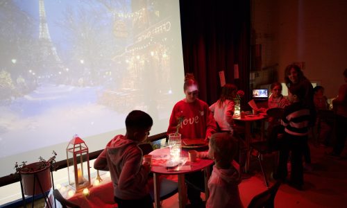 Group of students host a french cafe on the stage of a school gym.
