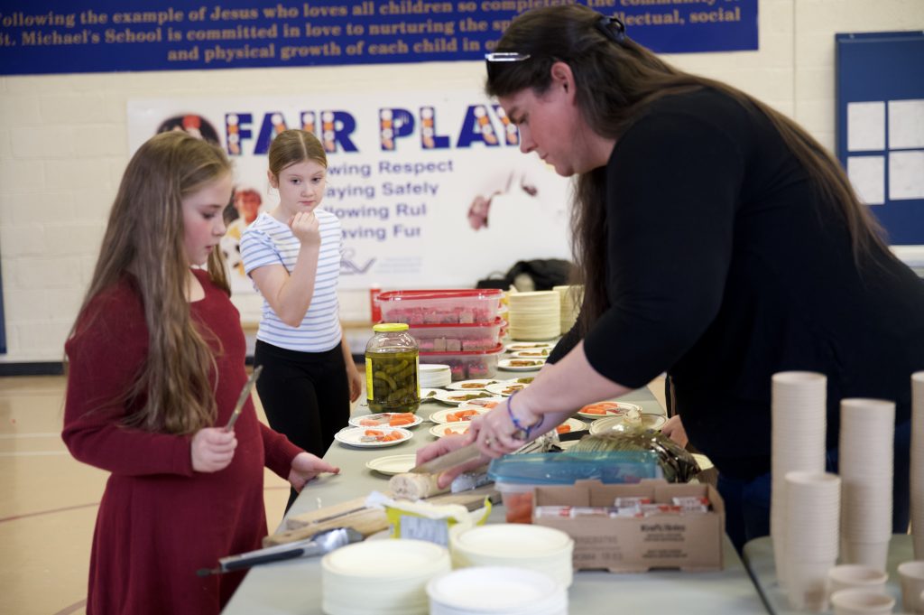 students work with an adult to prepare food