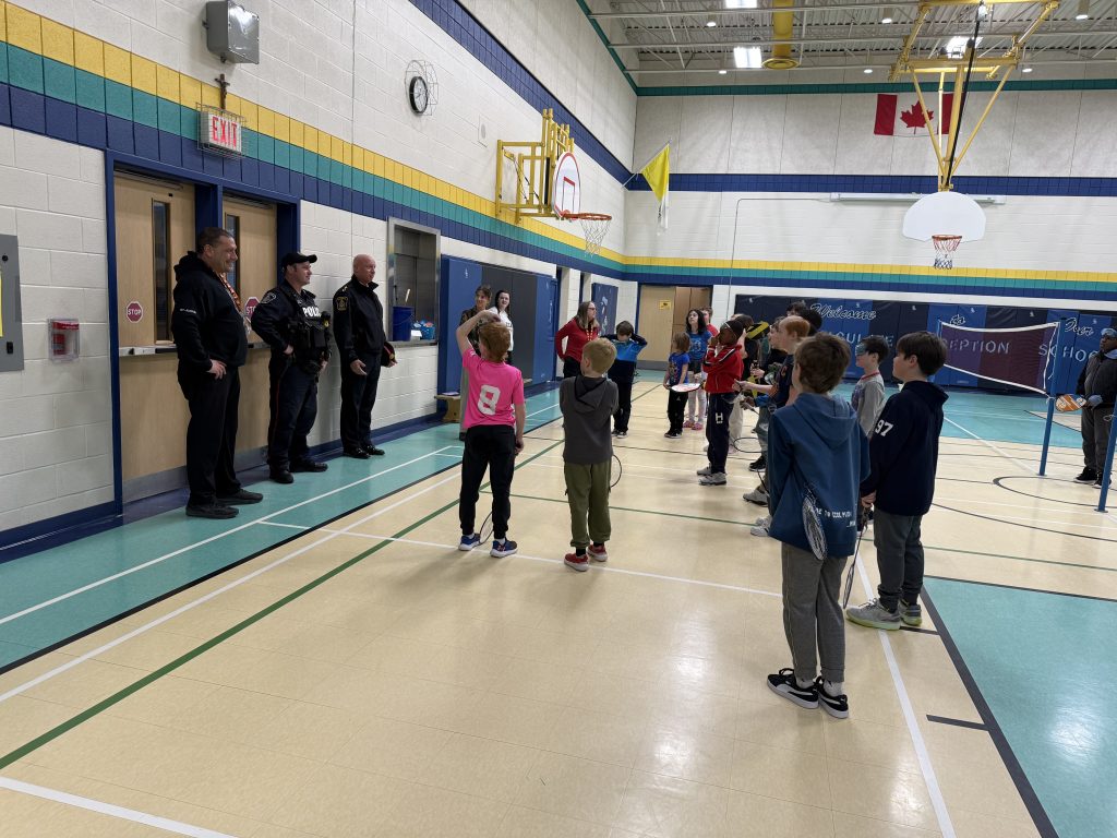 Police officers speak to students inside of a school gym.