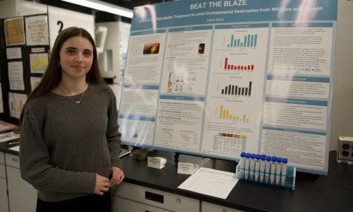 Student stands beside their project board at science fair.