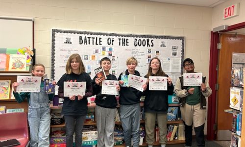 Students stand with certificates at Battle of the Books competition.
