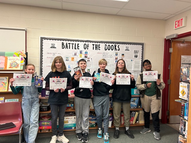 Students stand with certificates at Battle of the Books competition.