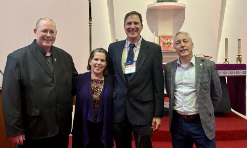 Four adults pose together for a photo.