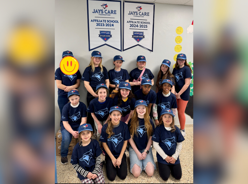 Students pose for a photo in front of two Jays Care banners.