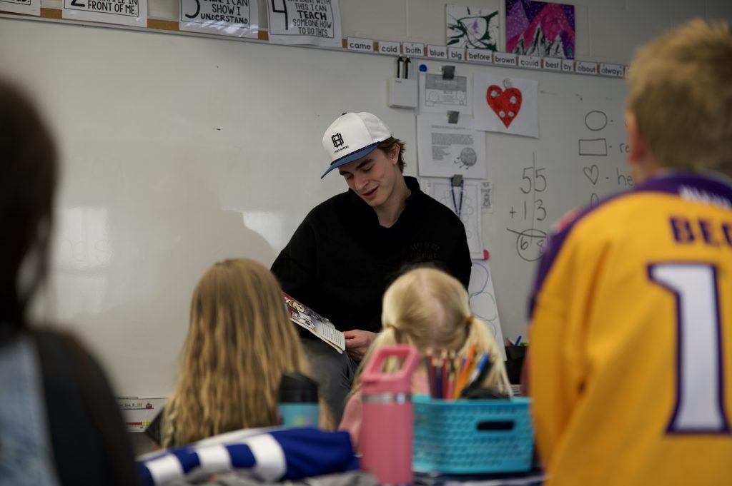 A hockey player reads a story to a group of children.