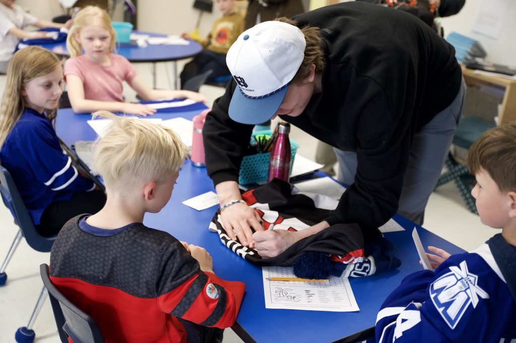 Hockey player signs an autograph for a child.
