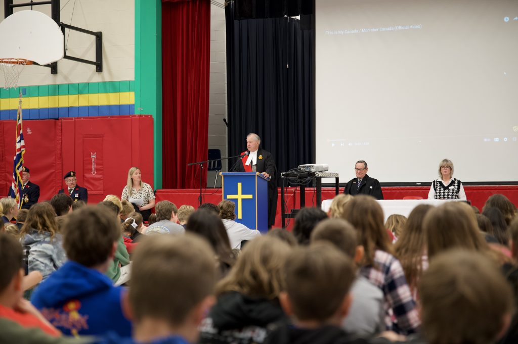 A judge presides over a school gymnasium that has been transformed into a courtroom for a citizen reaffirmation ceremony.