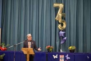 Adult stands in front of a school assembly in a gym.