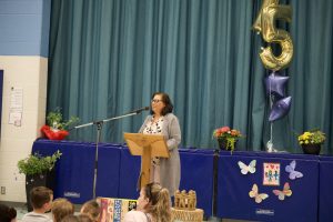 Adult gives a speech at a school assembly in a gym.