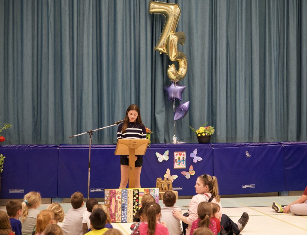 Student reads speech at assembly in a school gym.