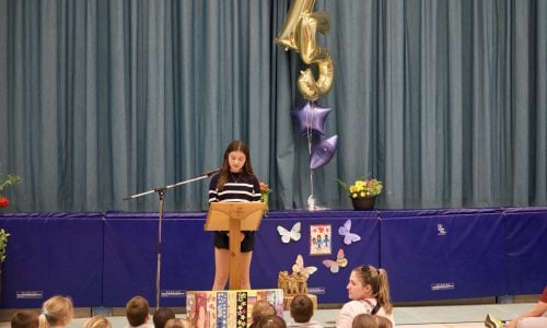 Student reads speech at assembly in a school gym.
