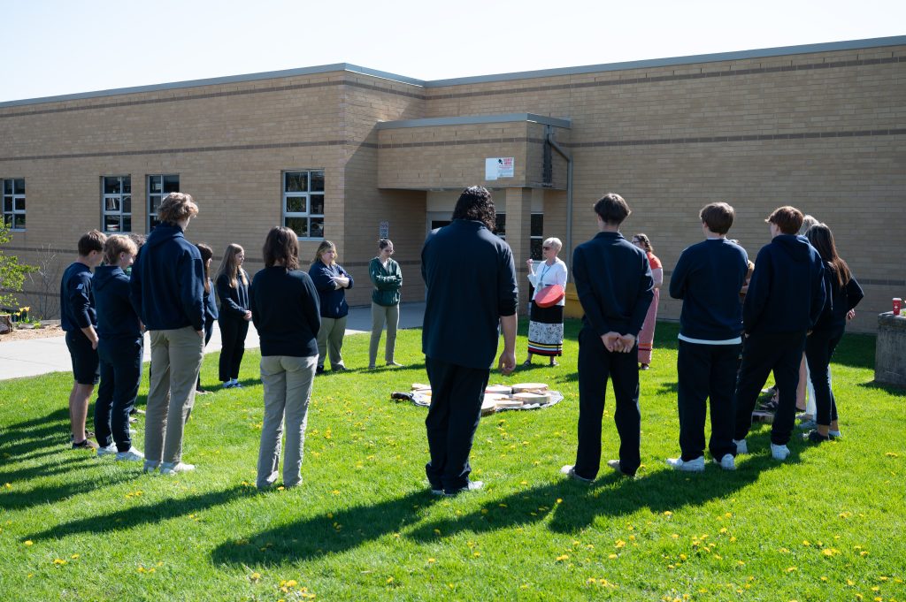 Students stand in a circle to listen to storytelling and take part in drumming with Indigenous Education team.