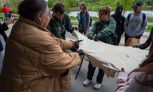 A group of students learns about deer hide scraping at an Indigenous skilled trades fair.