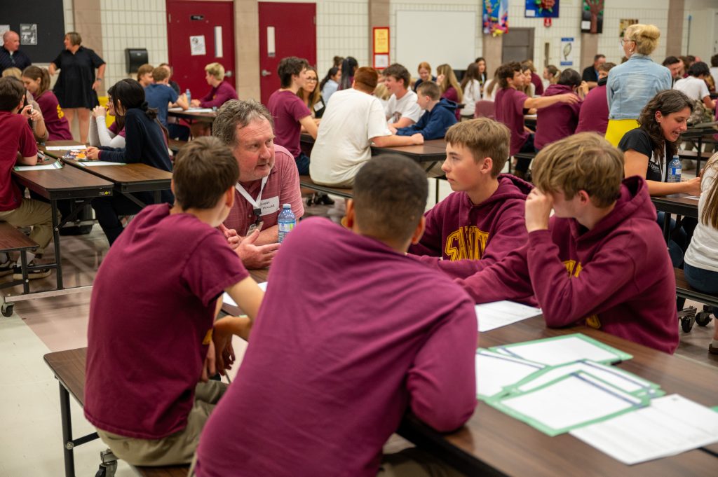 Group of students receive career coaching from industry professional at school assembly.