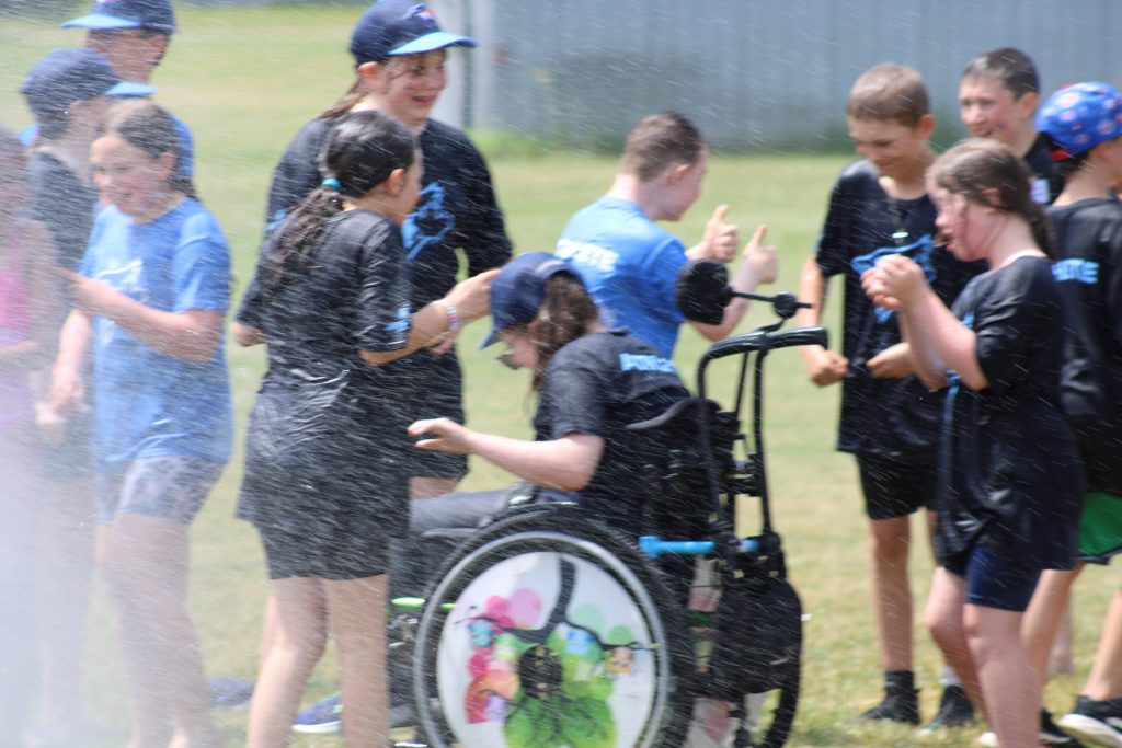 Children keep cool in the mist during a baseball game.