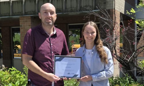 Student poses with adult after receiving bursary.