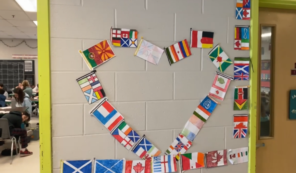Student made flags form a heart on a wall in a school.