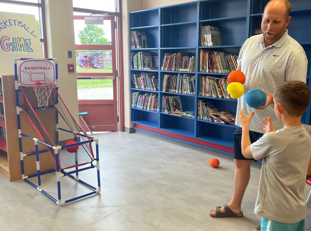 Adult hands basketballs to a student.