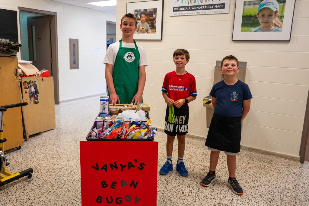 Three students pose with a coffee cart.