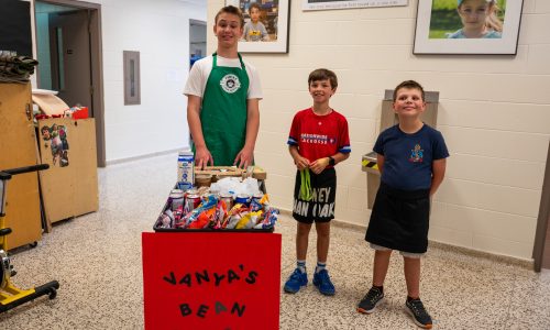 Three students pose with a coffee cart.
