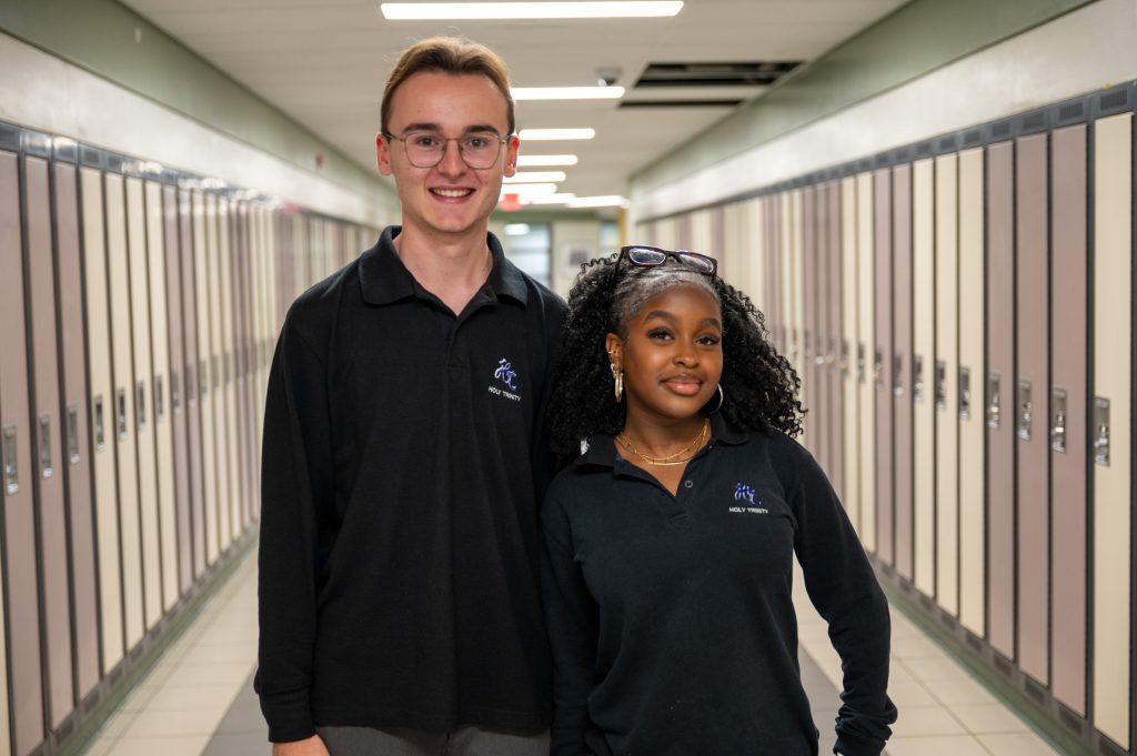 Two students pose together in a hallway at a school.
