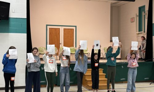Group of students holding placcards at an assembly.