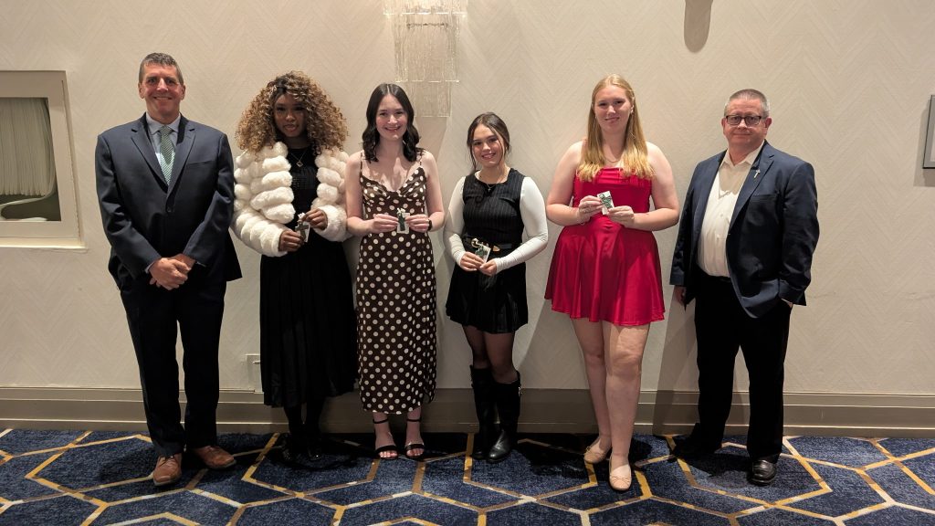 Four students pose with two adults at an awards gala.
