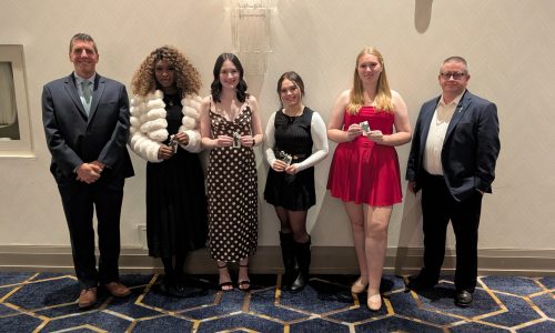 Four students pose with two adults at an awards gala.