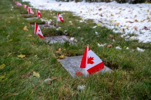 Graves of soldiers with Canadian flags on poppies placed on them for Remembrance Day.