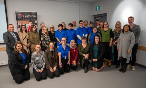 Group photo of adults and students in a library.