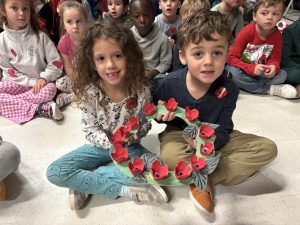 Young students hold a wreath for Remembrance Day.