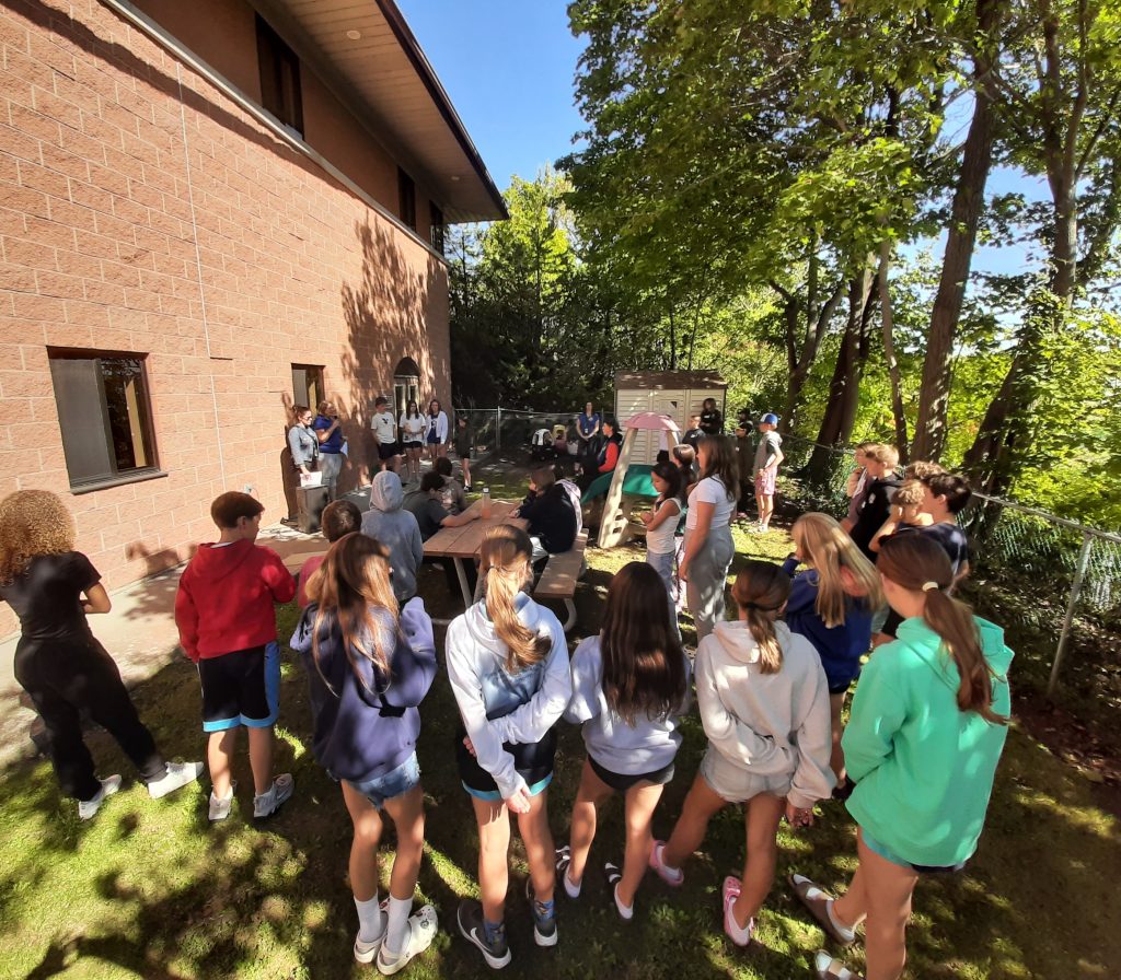 A group of students gather outdoors for a summit.