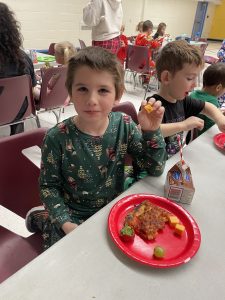 A boy smiles as he eats his lunch.