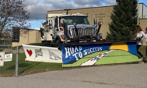 A snow plough with its blade decorated by students for a paint a plough event.