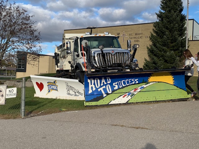A snow plough with its blade decorated by students for a paint a plough event.