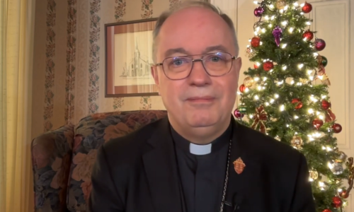 Bishop Daniel Miehm sits in front of a Christmas Tree to deliver his Christmas message.