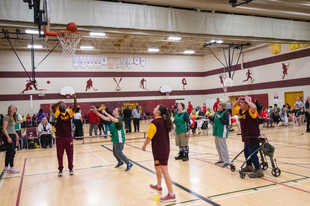 Student athletes play basketball in a school gym for a Special Olympics qualifier event.